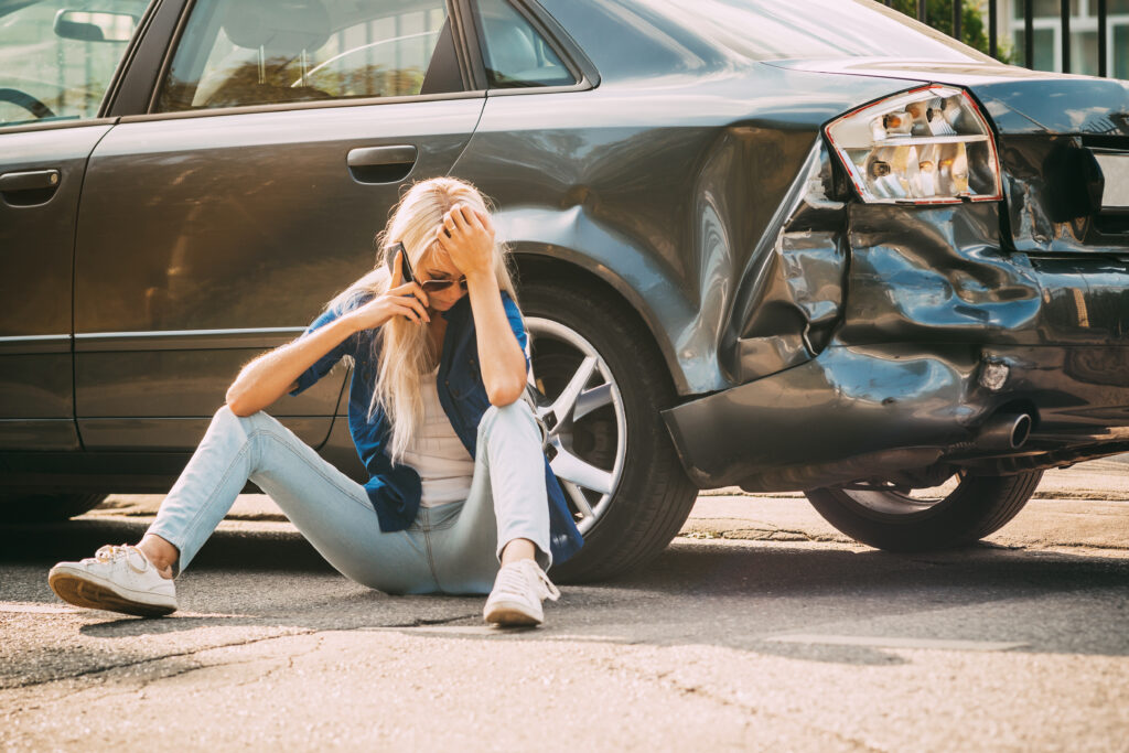 girl sits on the road, near the broken car and calls on the phone, calling for help.
